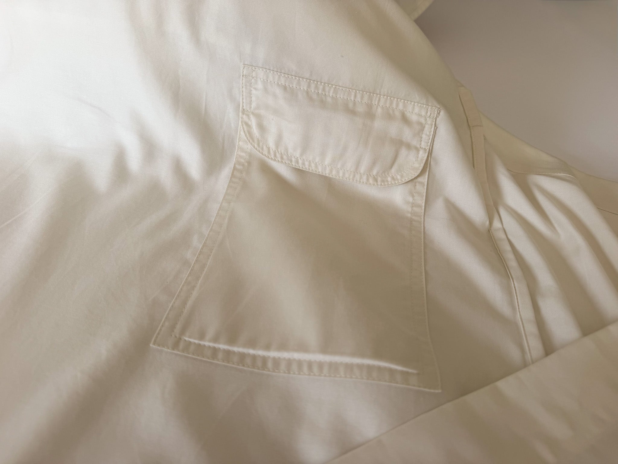 Macro view of the topstitching on the UpsideLuxe Sleep Sack's nighttime essentials pocket, showing the Supima cotton sateen craftsmanship