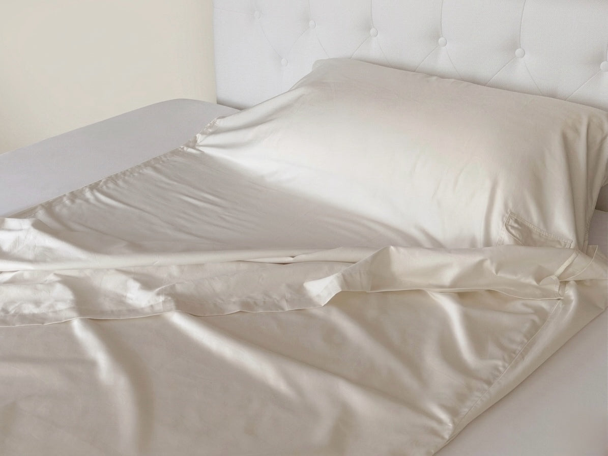 UpsideLuxe Sleep Sack in Egret ivory draped on a bed