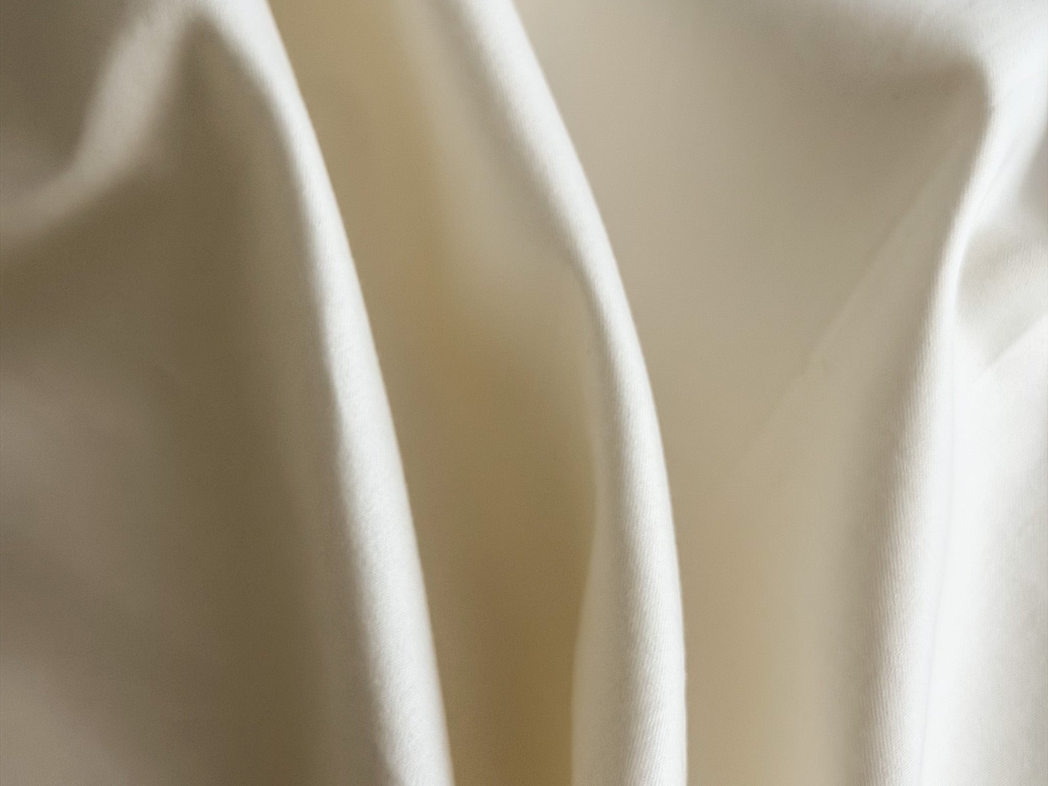 Close-up of UpsideLuxe Sleep Sack fabric in Egret showing sateen drape and texture